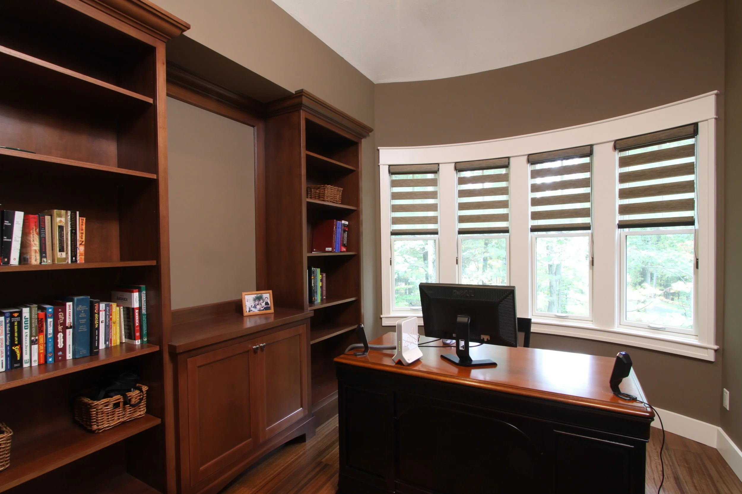 A home office with cherry built-in bookcases wrapping a curved bay window.
